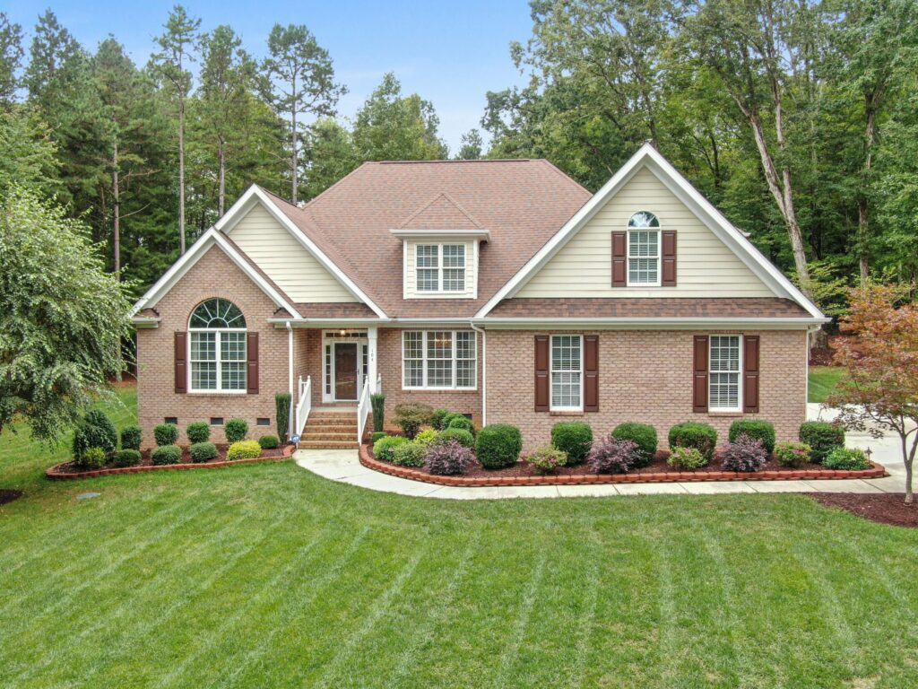 a brick house with grassy lawn and trees in the backyard