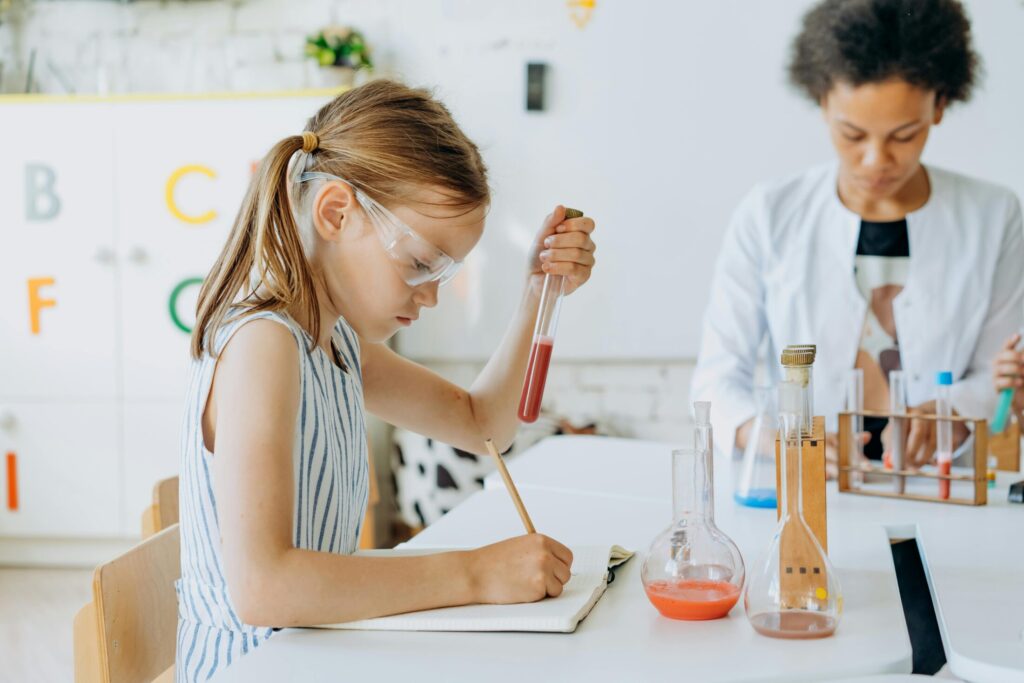 a girl holding a test tube white writing in a notebook