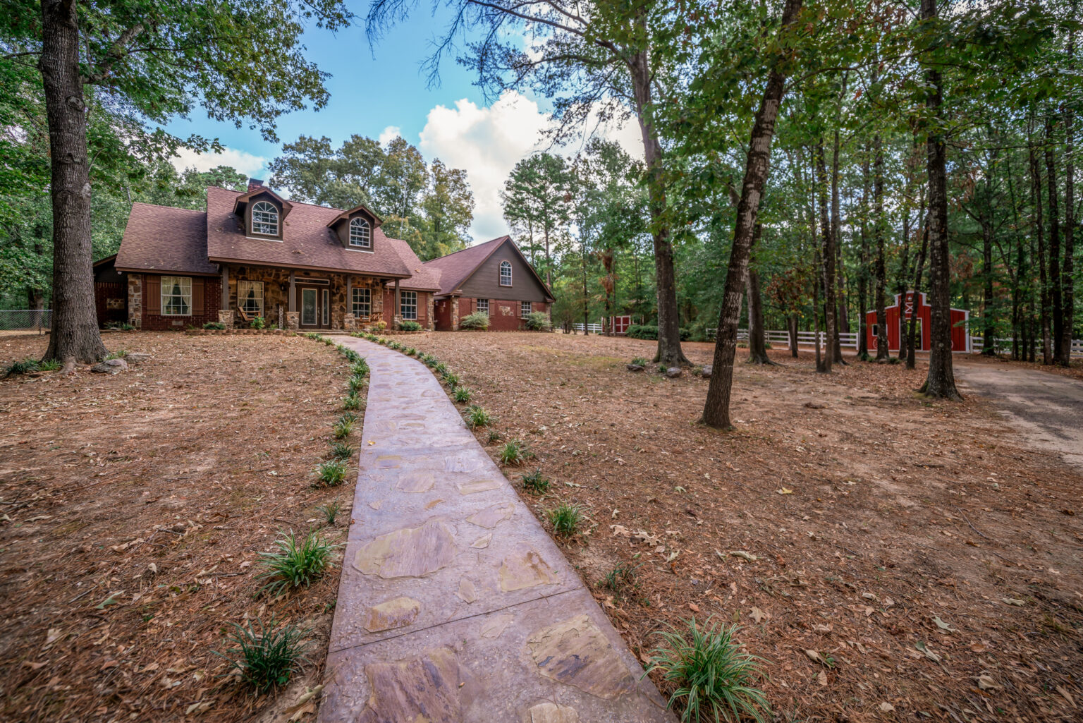 a stone and wood-sided house located on a large, wooded property