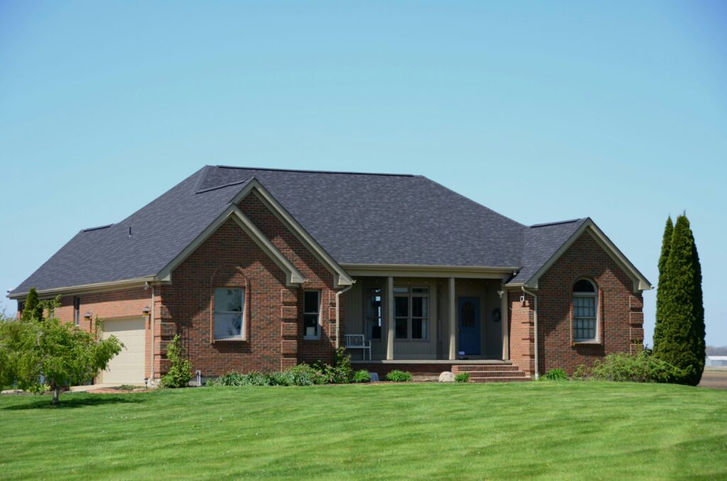 a brick house with a green lawn and blue sky
