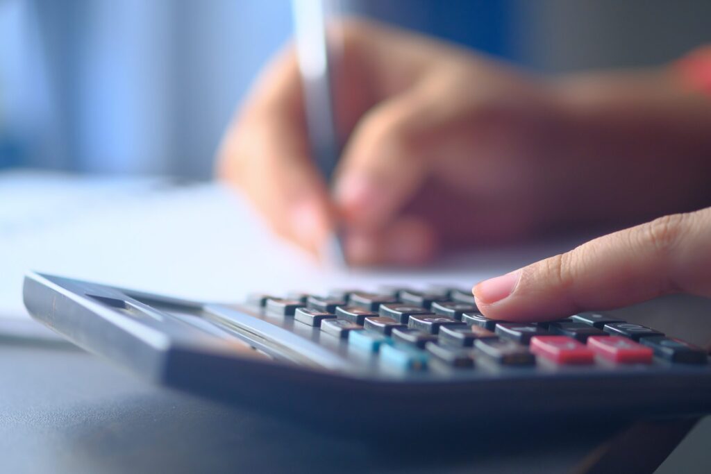 a finger on a calculator while writing on the other hand