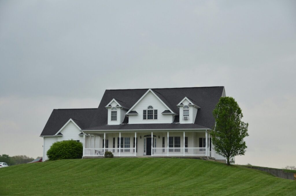 a white house sits a top a green hill