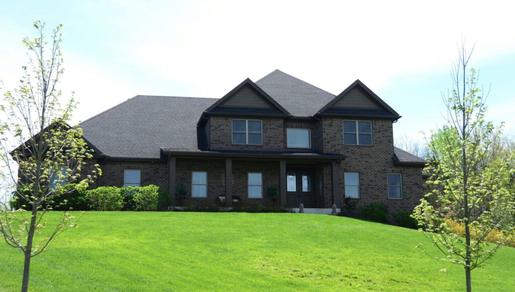 a large brick house sitting on top of a lush green field